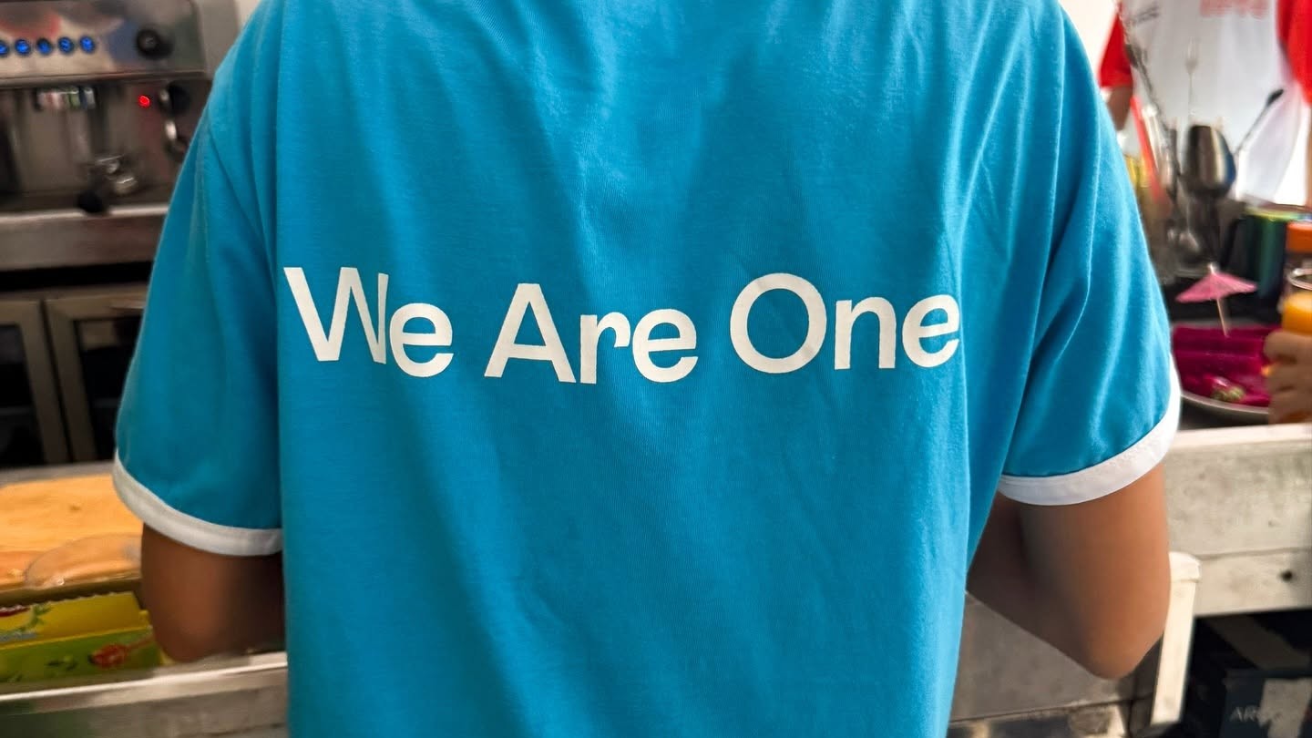 KOTO staff member in a blue shirt with the words We Are One on the back.